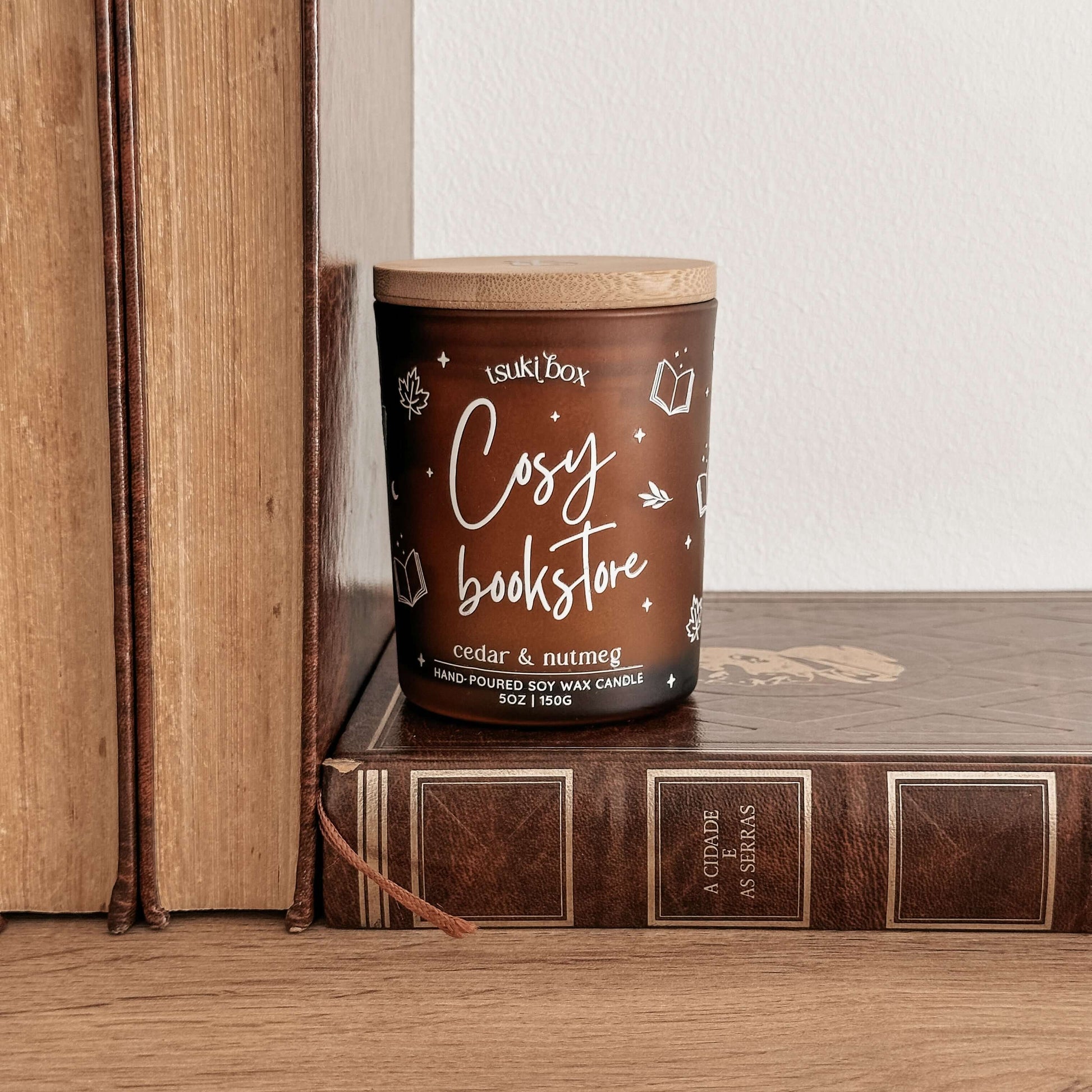 vela de soja artesanal com aroma a cedro e nutmeg, em cima de livros antigos